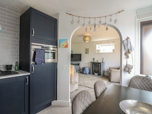 A modern kitchen with dark cabinetry, a built-in oven, and a hanging light fixture. - 38 St Margarets (Dover)