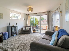 A living room with a fireplace, a sofa, a television, and a view of the outside. - 38 St Margarets (Dover)