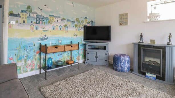 A living room with a mural, a flat-screen TV, a fireplace, and a cozy seating area. - 38 St Margarets (Dover)