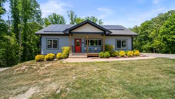 A two-story house with a red door, solar panels, and a front porch.