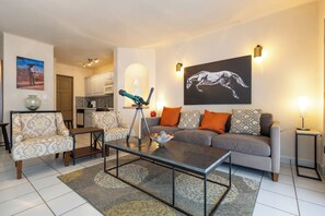 A living room with a sofa, armchairs, a coffee table, and a dining area with a kitchen in the background. - Gorgeous views 1BR pool, near beaches & downtown, concierge service included (San José del Cabo)