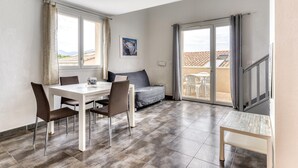 Una habitación moderna con una mesa de comedor, sillas, un sofá y un balcón con vistas.