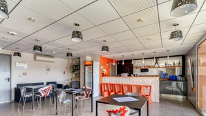 Un moderno vestíbulo de hotel con zonas de estar, una recepción y una cocina visible al fondo.