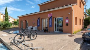 Un edificio con recepción, una bicicleta estacionada afuera y un cielo azul despejado.