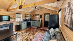 A log cabin interior with a kitchen, dining area, and a large window.