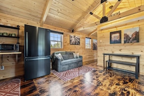 A wooden cabin interior with a kitchen, a sofa, and a dining table.