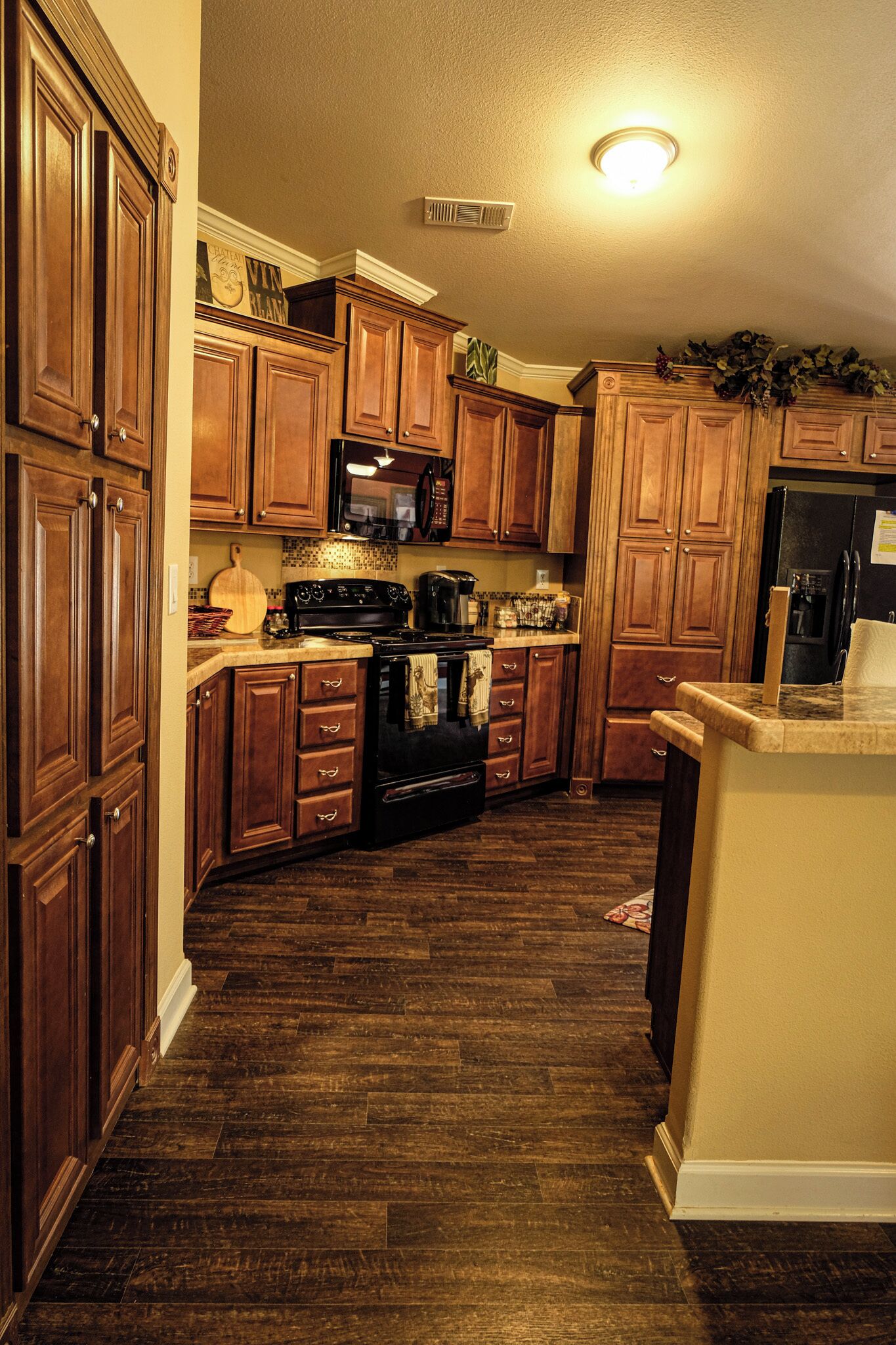 A kitchen with wooden cabinets, a microwave, stove, and a refrigerator.