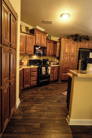 A kitchen with wooden cabinets, a microwave, stove, and a refrigerator.