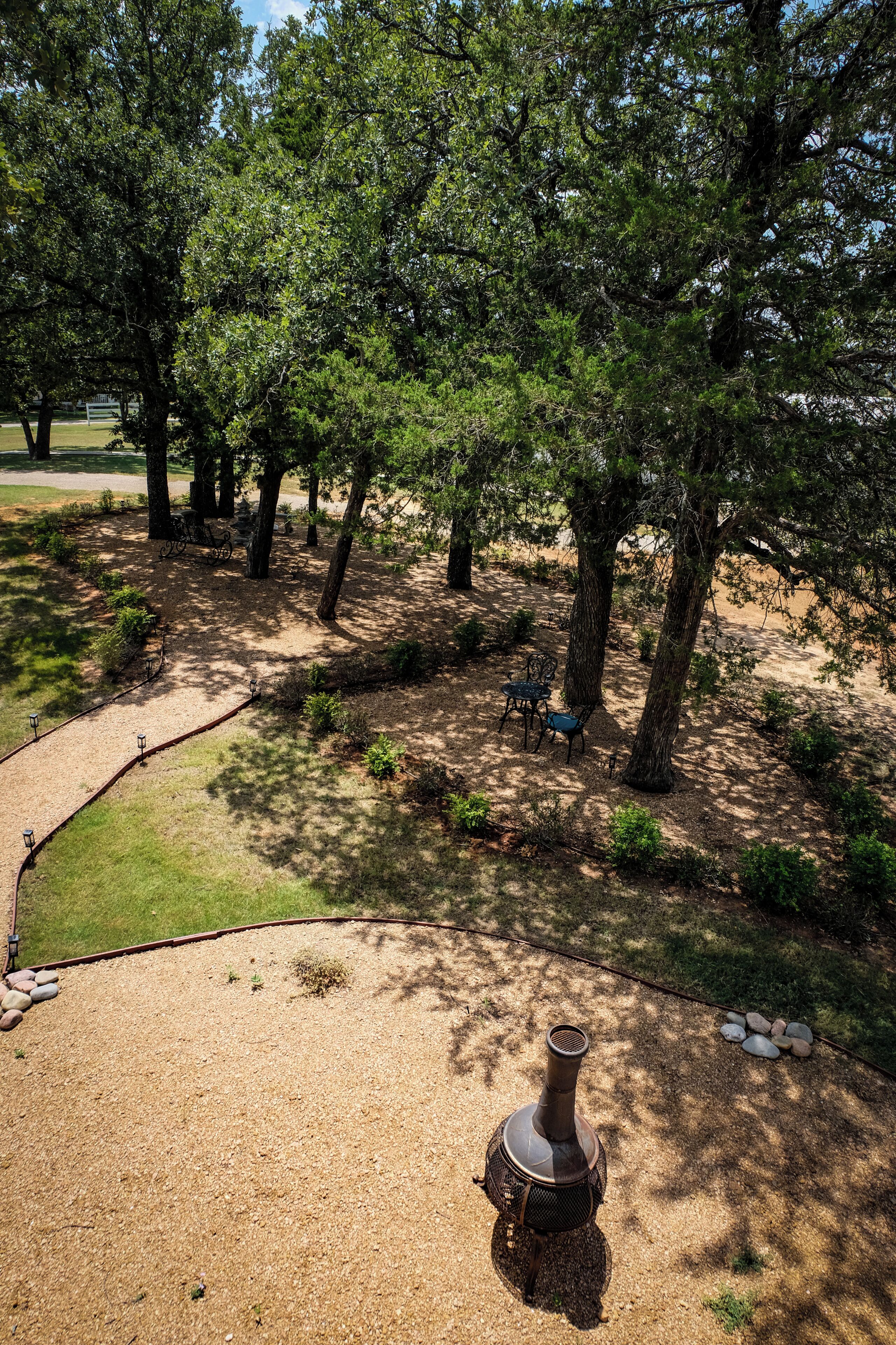 A park with a gravel path, benches, and a decorative fire pit.