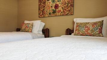 Ein Hotelzimmer mit zwei Betten, jeweils mit weißer Bettwäsche und Kissen mit Blumenmuster.