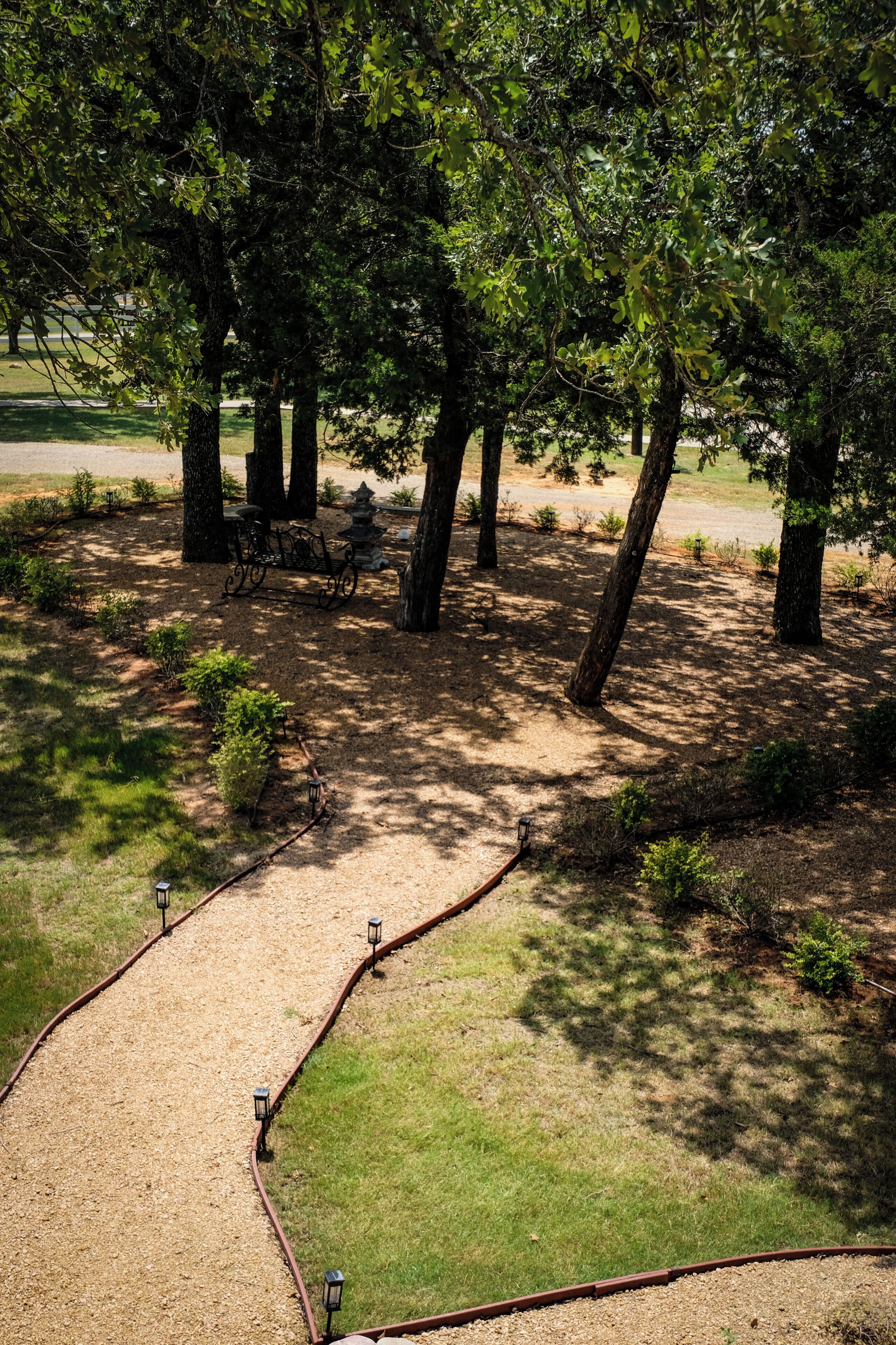 A park with a gravel path, trees, and benches.