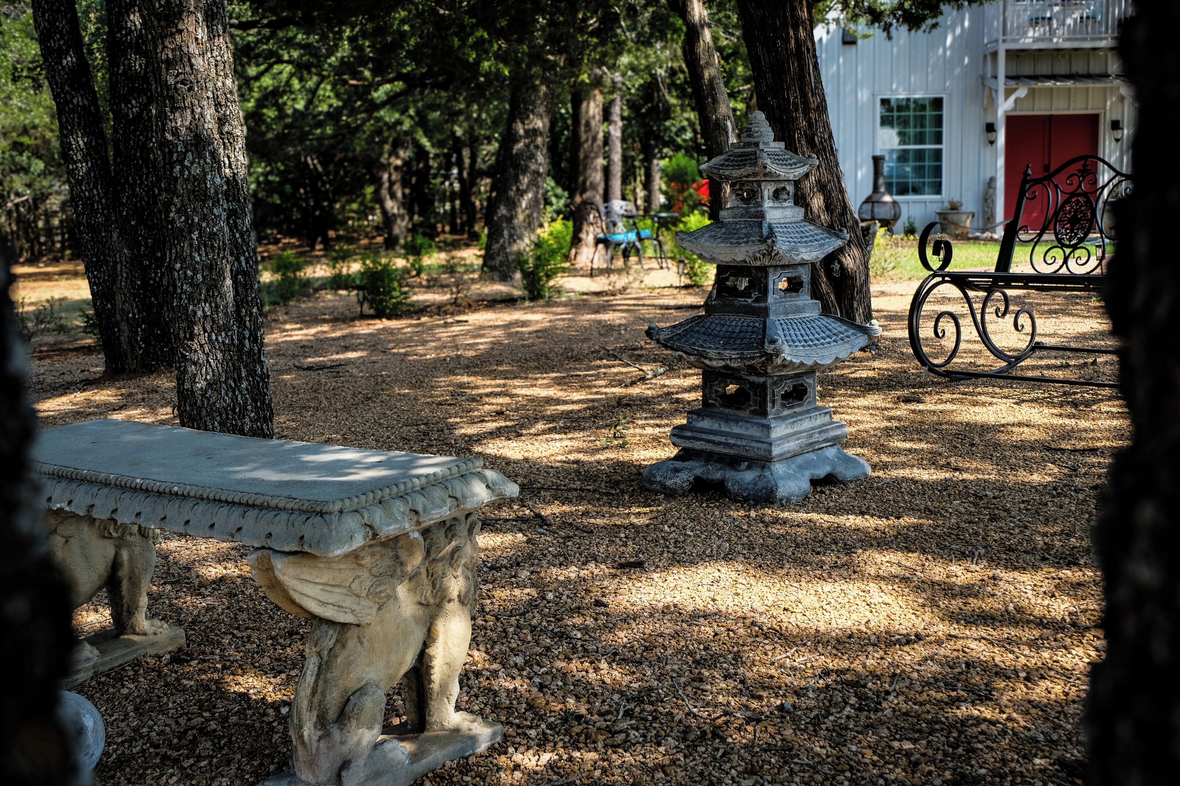 A stone lantern in a garden with trees and a bench.