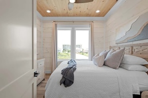 Un dormitorio con una cama grande, cabecera de madera y vistas al exterior.