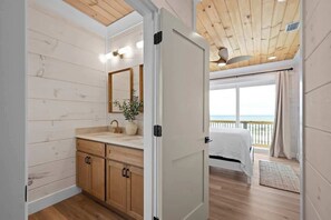 A bedroom with a wooden ceiling, a large window with curtains, a bed, and a view of the sea. - 8-Bedroom Beachfront Home in Gulf Shores with Private Pool & Arcade (Gulf Shores)