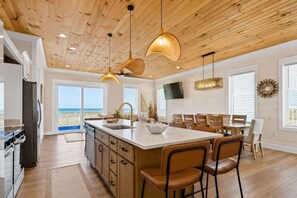 A spacious kitchen with a large island, wooden ceiling, and a view to the outside. - 8-Bedroom Beachfront Home in Gulf Shores with Private Pool & Arcade (Gulf Shores)