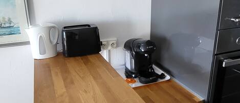 Ett kök med en bänkskiva i trä, en kaffebryggare, en brödrost och en vattenkokare.