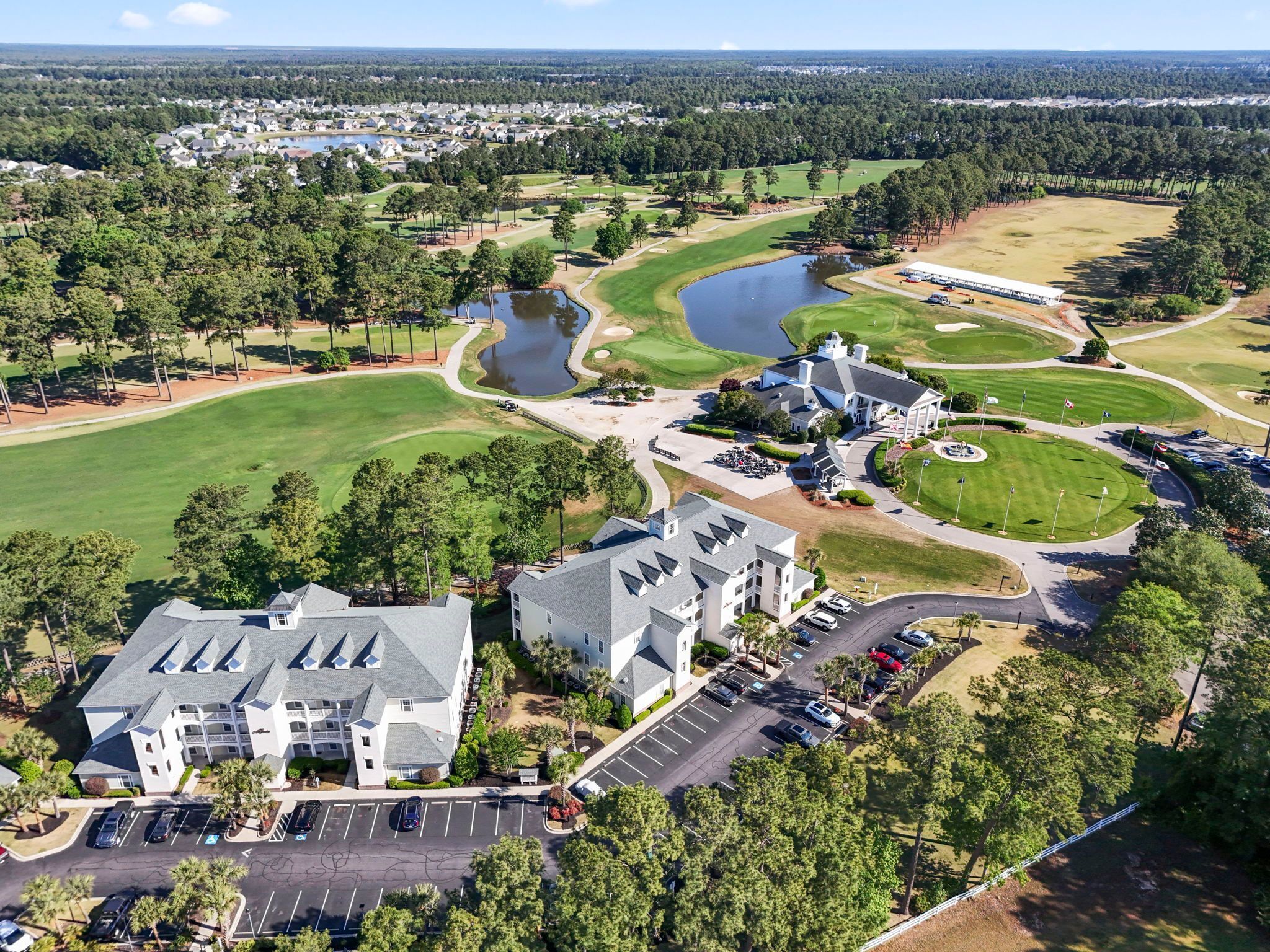 Ein Luftbild eines Golfplatzes mit Clubhaus, Parkplätzen und einem See.