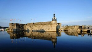 Un’antica fortezza con una torre dell’orologio, immersa in acque calme che riflettono la sua struttura.