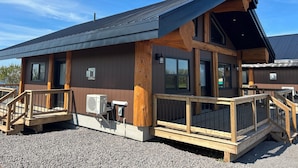 Un bâtiment à deux étages doté d’une terrasse en bois, de grandes fenêtres et d’un toit en pente.