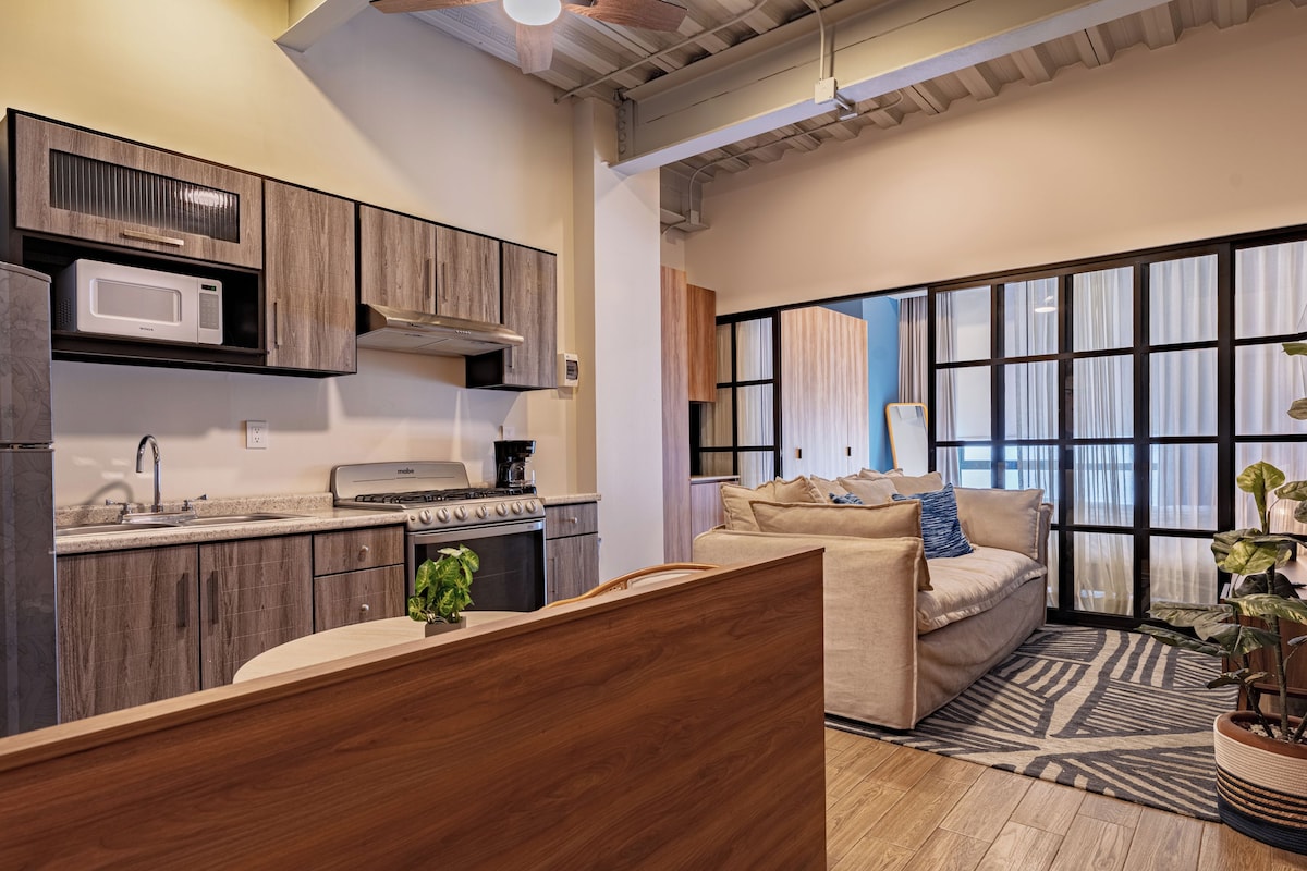A modern kitchen with a built-in microwave, stove, and oven. There is a wooden dining table with a plant on it.