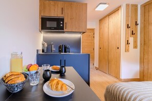 Eine kompakte Küche mit Mikrowelle, Kaffeemaschine und Frühstücksprodukten auf der Arbeitsplatte.