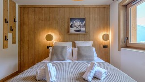 Une chambre à coucher avec une tête de lit en bois, deux lampes de chevet, un tableau encadré et un lit avec des serviettes.