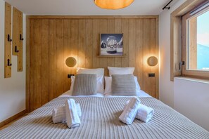 Ein Schlafzimmer mit einem hölzernen Kopfende, zwei Nachttischlampen, einem gerahmten Bild und einem Bett mit Handtüchern.