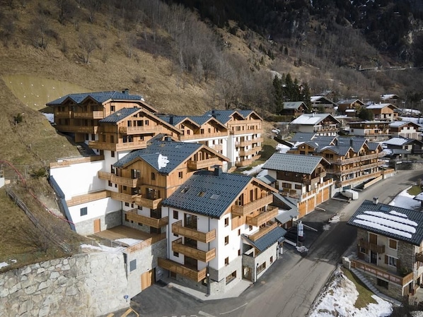 Eine Gruppe von Holzhäusern im Chalet-Stil mit Balkonen, die eng beieinander liegen, umgeben von einer Berglandschaft.