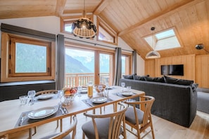 Ein Holzinterieur mit Essplatz, einer Couch und einem an der Wand befestigten Fernseher.