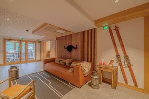 A modern interior with a wooden slat wall, a leather sofa, and skis leaning against the wall. - Wifi, 300m from resort center, balcony, parking, tv, ski locker, 93m², Champagny-en-Vanoise (Champagny-en-Vanoise)
