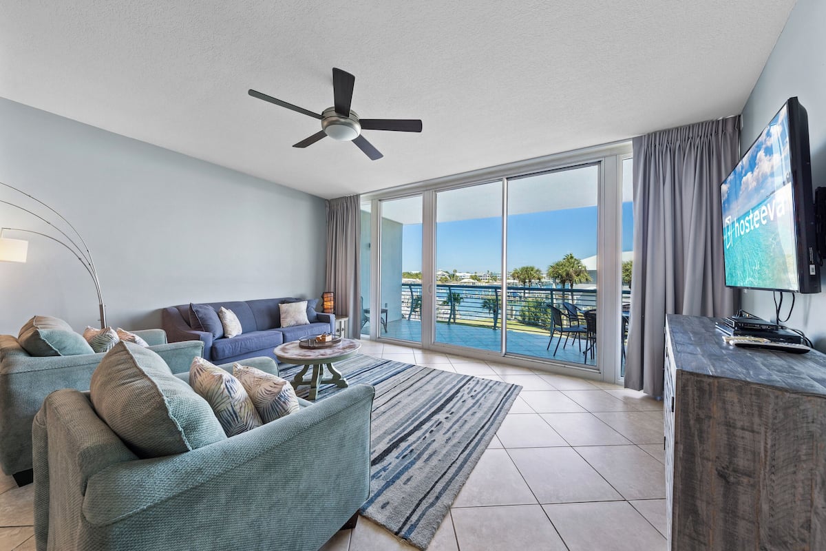 A modern living room with a sofa, a coffee table, a TV, and a balcony with a view.