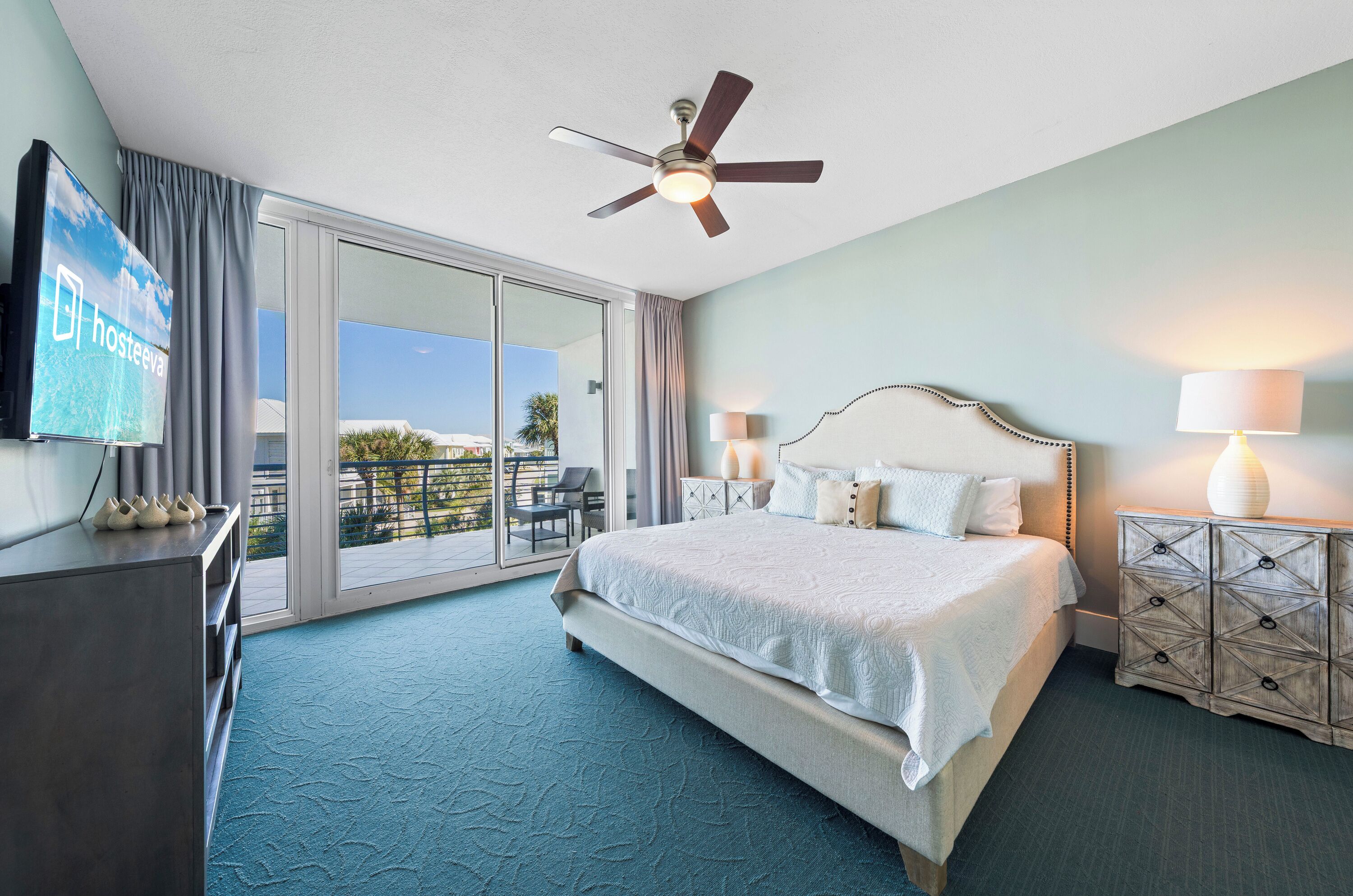 Ein Hotelzimmer mit Bett, Deckenventilator, Fernseher und Blick ins Freie.