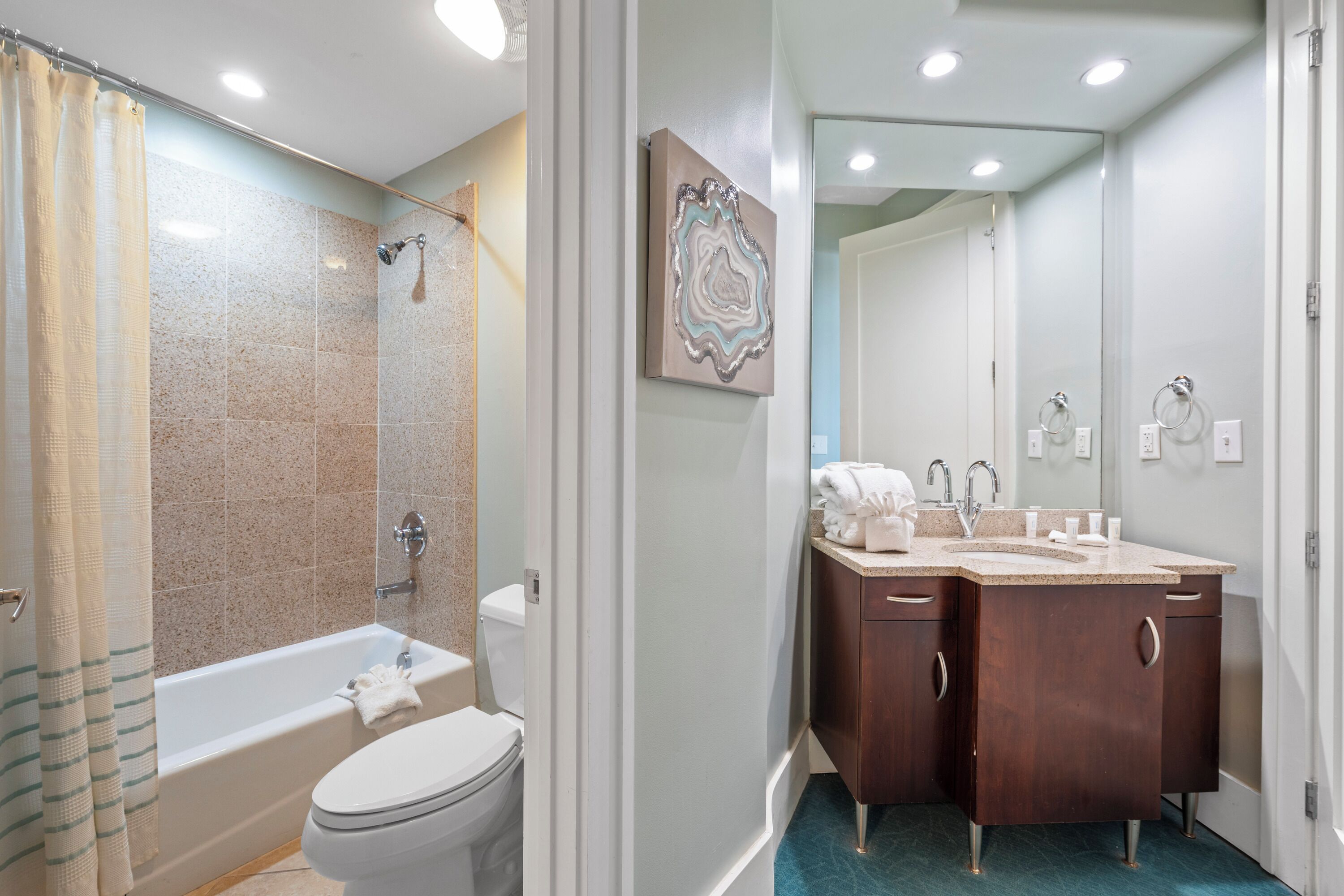 A bathroom with a bathtub, toilet, and double vanity with a mirror.
