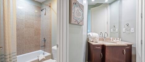 A bathroom with a bathtub, toilet, and double vanity with a mirror.