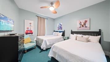 Habitación de hotel con dos camas, ventilador de techo, obras de arte en las paredes, televisor y escritorio con computadora.