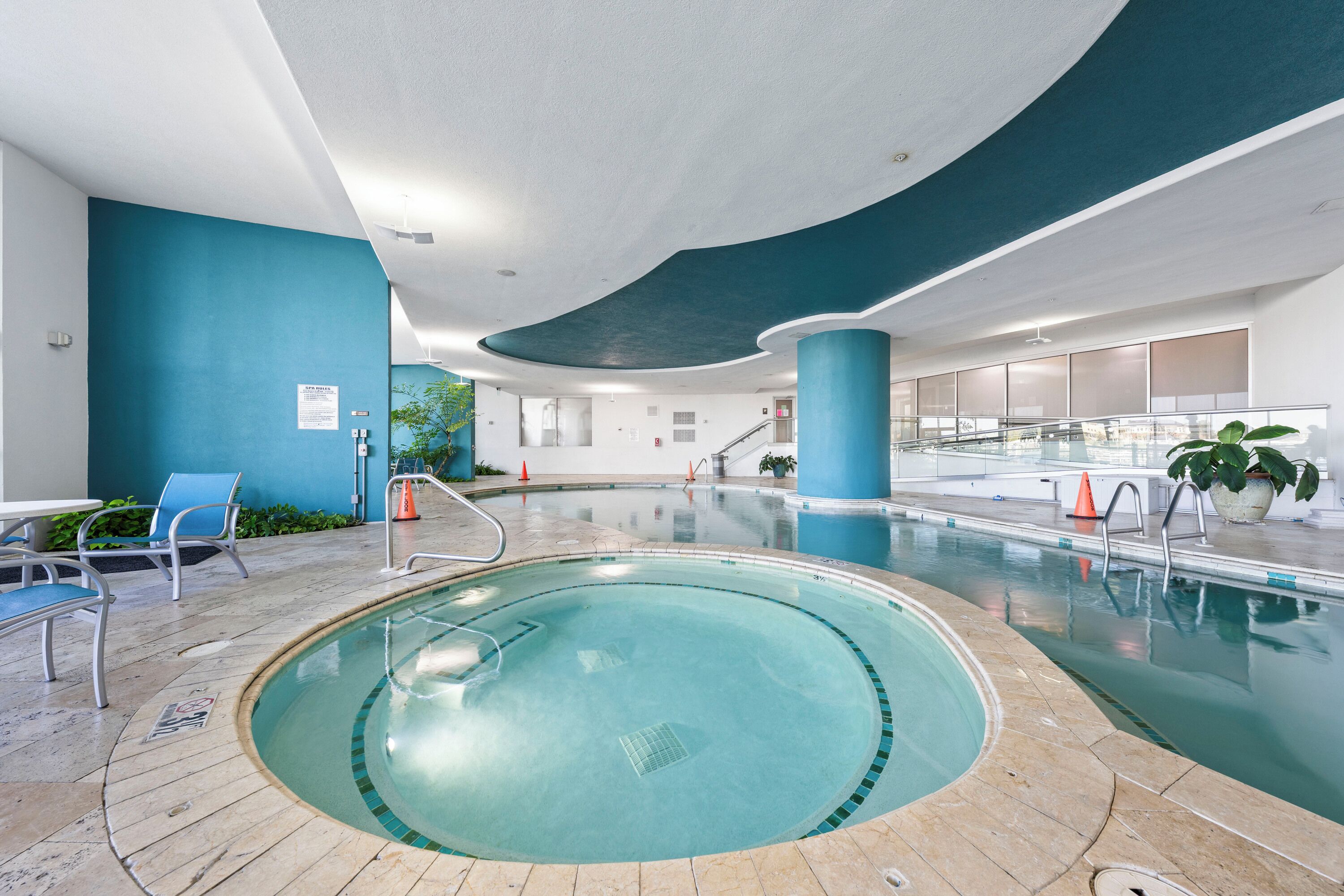 En inomhuspool med en böjd design, blå väggar och ett kaklat golv.
