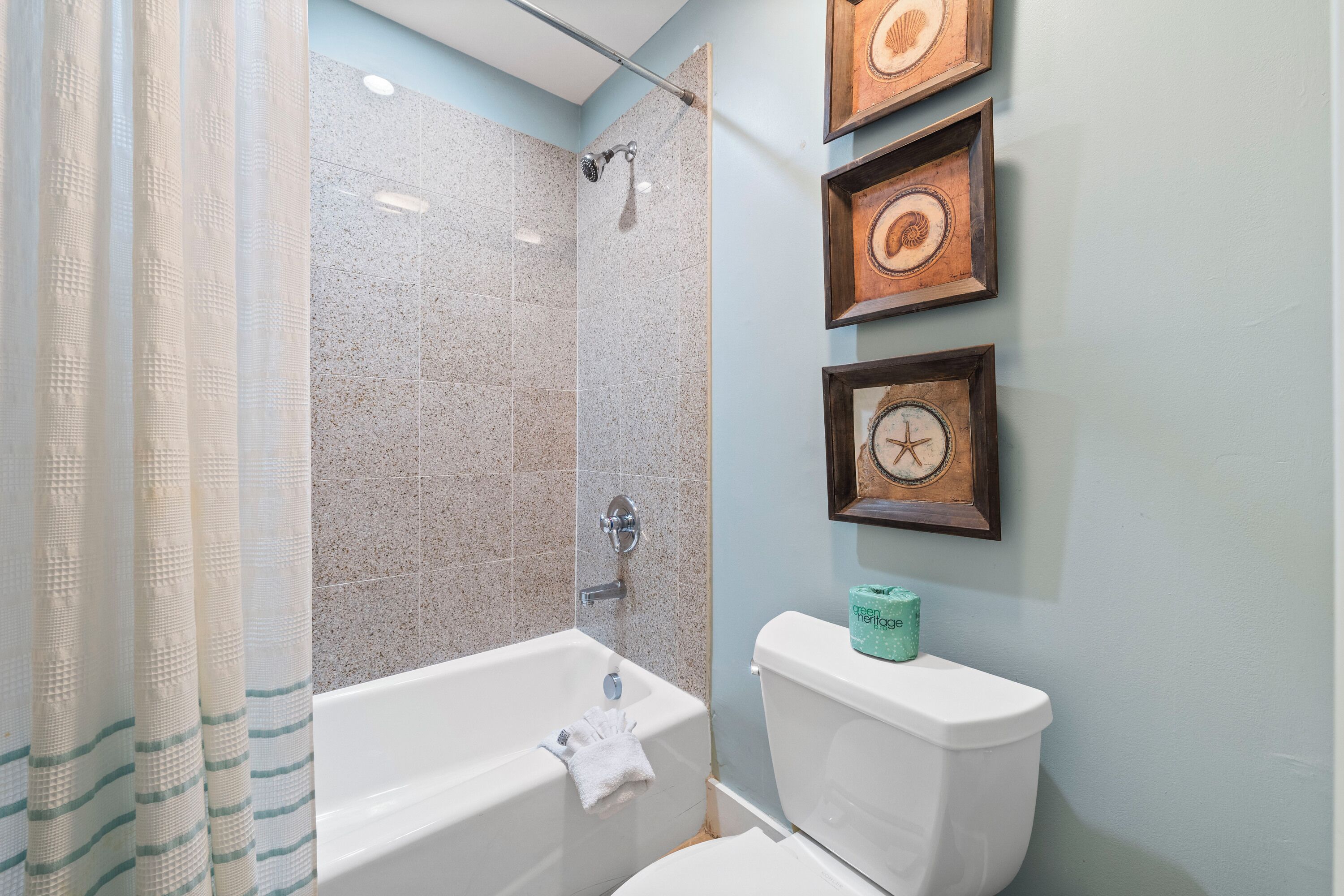 Un baño con bañera, inodoro y cortina de ducha.