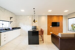 Uma cozinha moderna com ilha preta, armários brancos e parede de destaque em madeira.