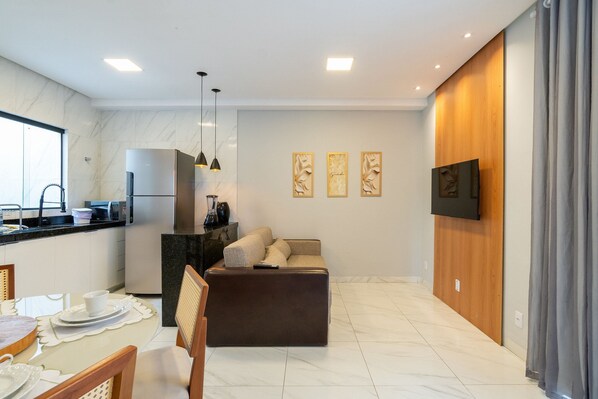 A modern kitchen with a refrigerator, microwave, and dining area with a table and chairs.