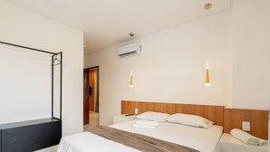 Une chambre d’hôtel équipée d’un lit, de tables de chevet, d’un appareil de climatisation et de lampes suspendues.