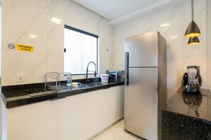 Uma cozinha moderna com geladeira de aço inoxidável, micro-ondas e cafeteira.