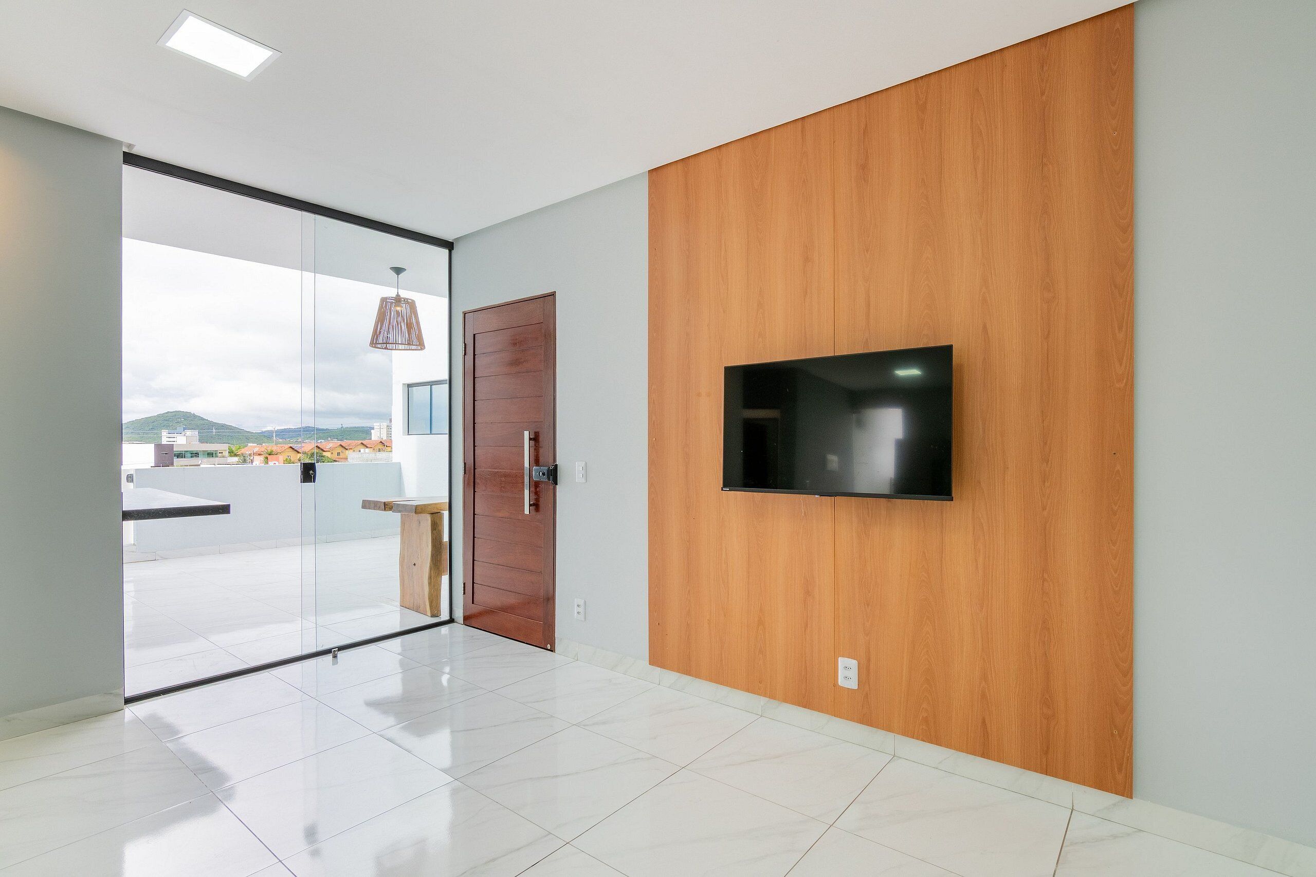 Ein modernes Interieur mit Glastür zum Balkon, einem an der Wand montierten Fernseher und einer Holzwand.