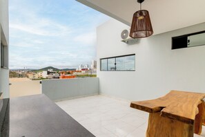 Une chambre moderne avec une grande fenĂȘtre, une table en bois et un luminaire suspendu.