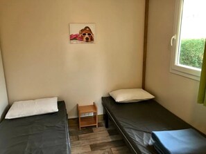 A small room with two beds, a small table, a window, and a picture on the wall. - Camping 3 étoiles - Parc aquatique - ccbfgeb (Sainte-Eulalie-en-Born)