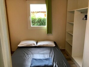 A bedroom with a bed, a window with a curtain, and a wardrobe. - Camping 3 étoiles - Parc aquatique - ccbfgeb (Sainte-Eulalie-en-Born)