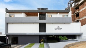 Un edificio moderno con techo plano, un letrero que dice 'Bauten HOME STAY' y la entrada a un garaje.