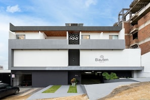 Un bâtiment moderne doté d’un toit plat, d’une enseigne indiquant « Bauten HOME STAY » et d’une entrée de garage.