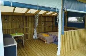 Ein Zeltraum mit einem Bett, einem Schreibtisch und einem Stuhl.