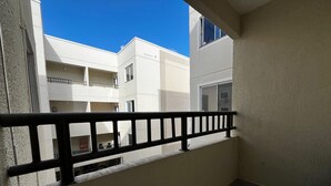 A balcony with a black railing, a view of adjacent buildings, and a clear blue sky. - Caminho das Bromélias Lodging – Caruaru (Caruaru)
