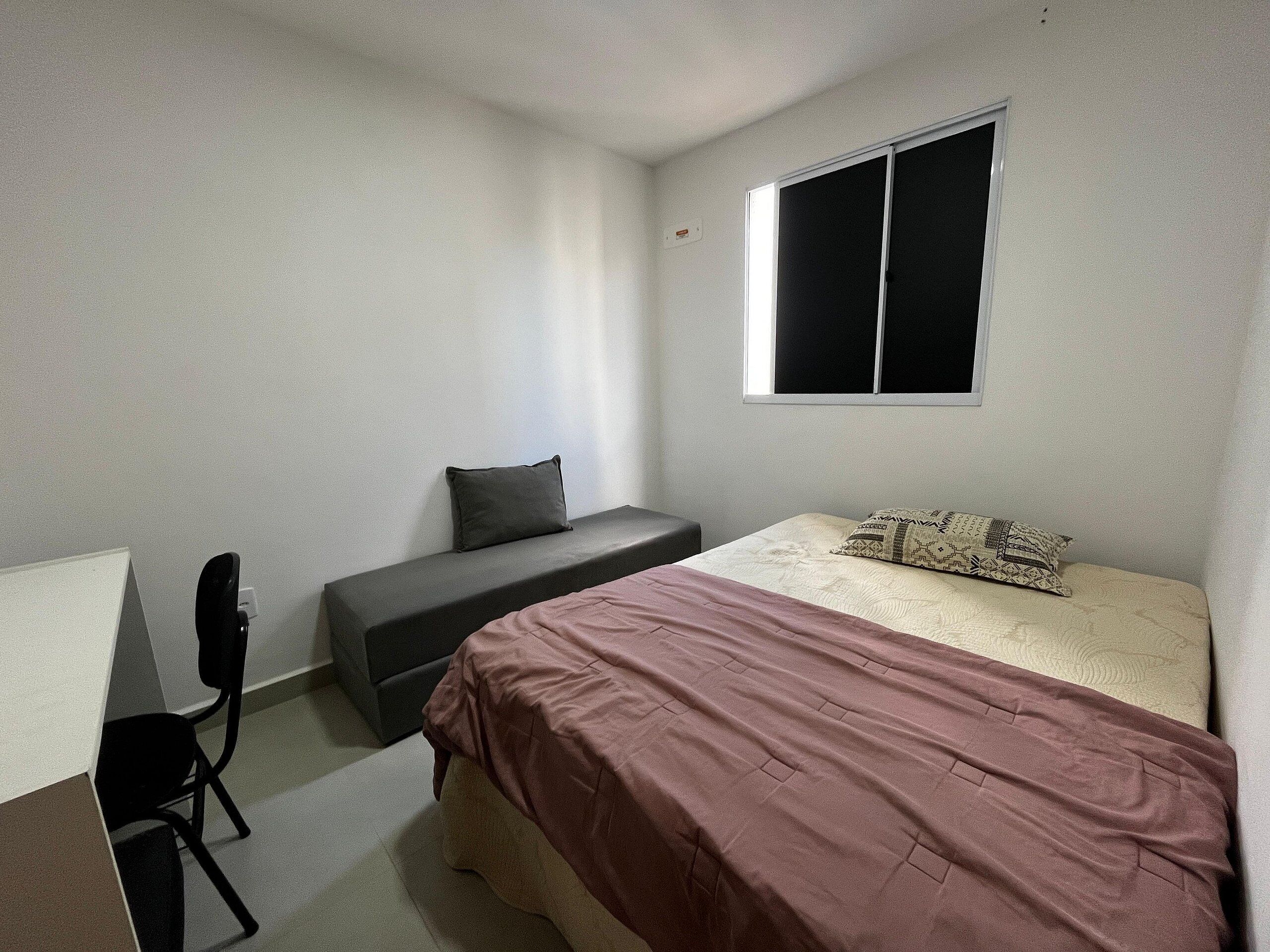 Una camera da letto con un letto, una scrivania, una sedia e una finestra.